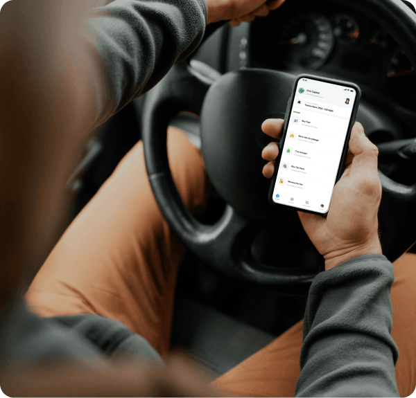 Driver holding a phone with the BetaDriva app open, showing actions to buy fuel, record mileage, check in on arrival, buy car parts and service the car